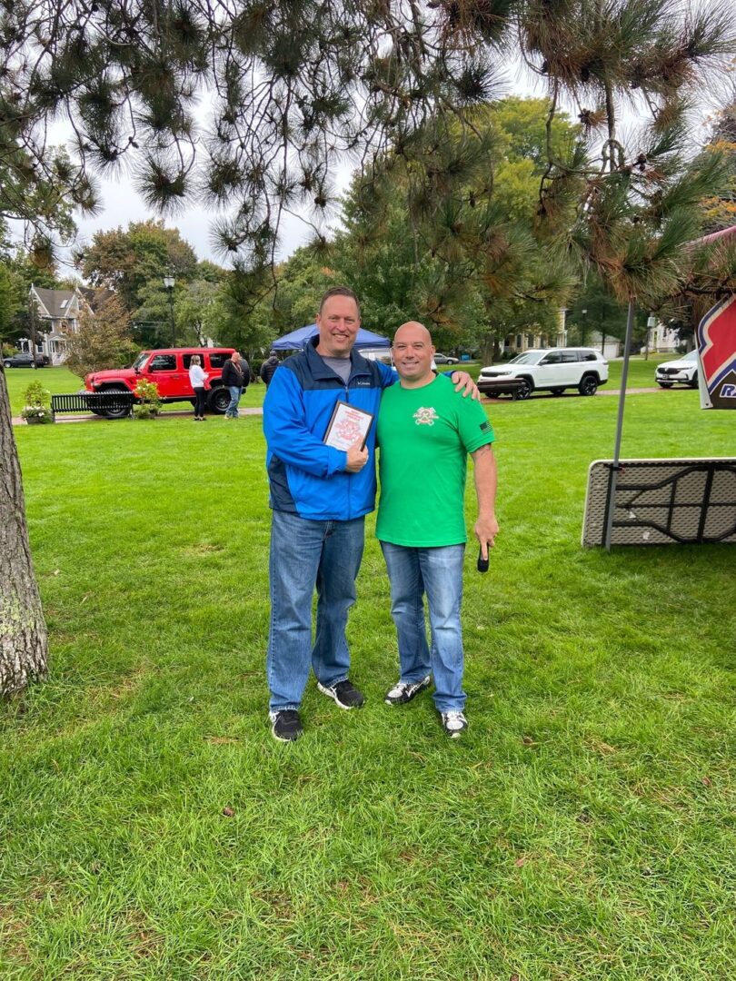 Two men standing in a park holding papers.
