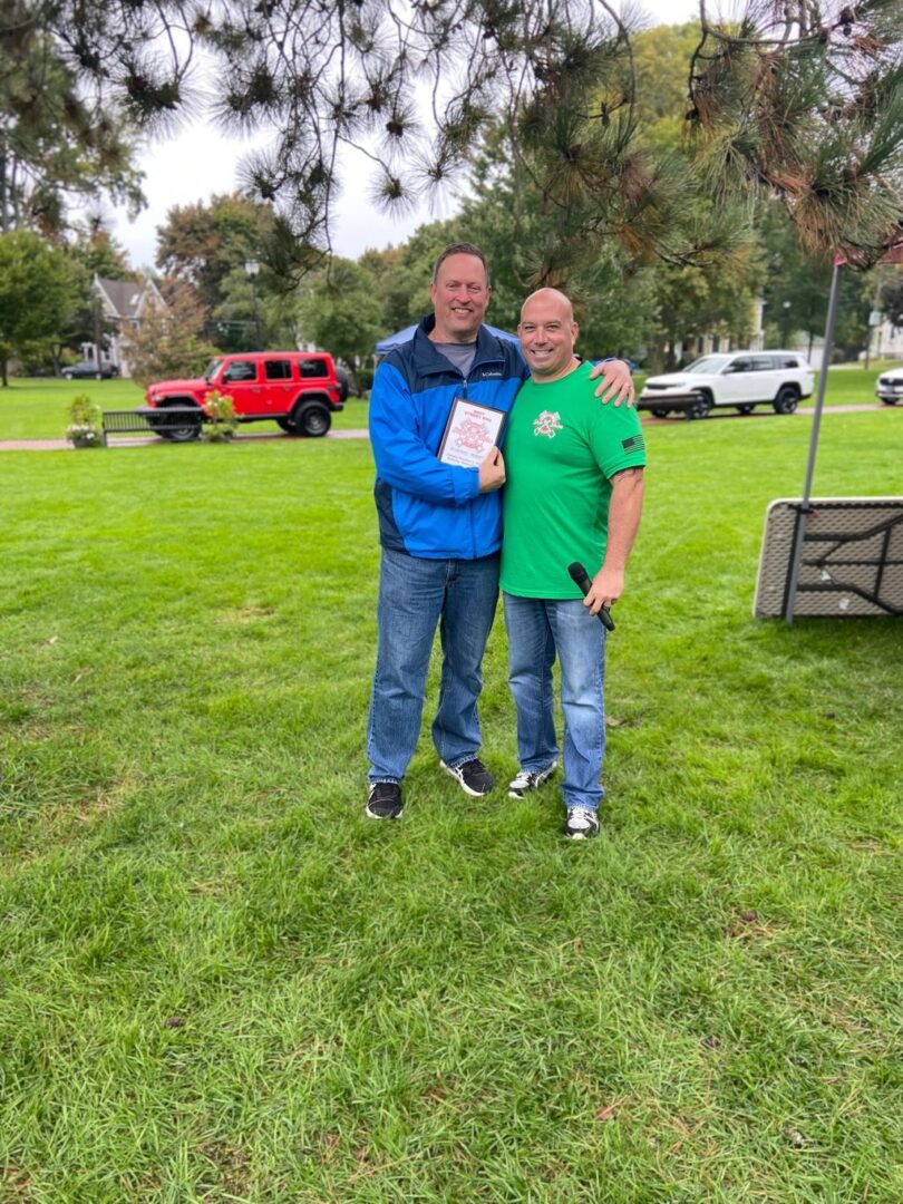 Two men standing in a park holding papers.